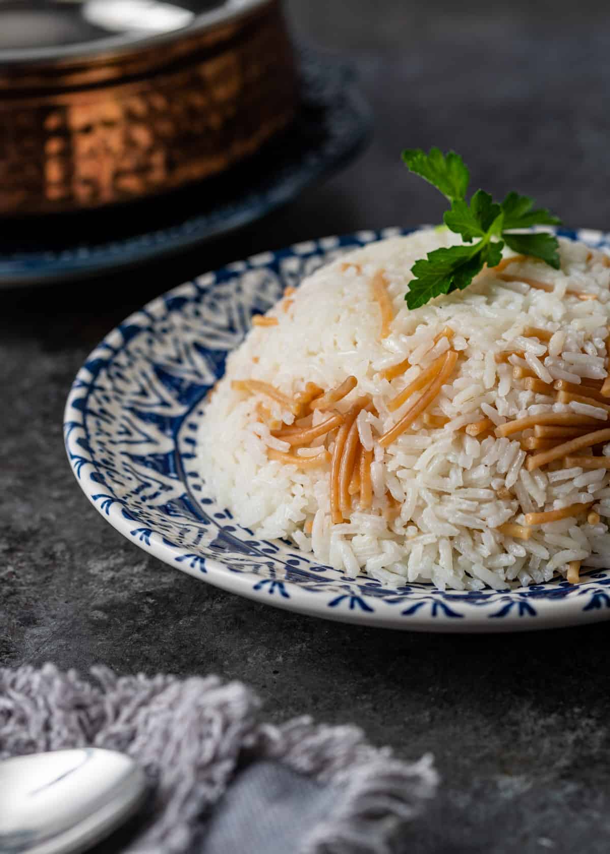 a blue and white plate with Egyptian rice with vermicelli and fresh herbs on top