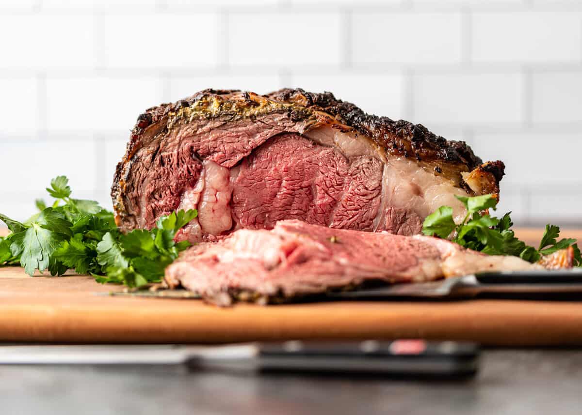 side view: prime rib roast over fresh herbs with a slice taken out