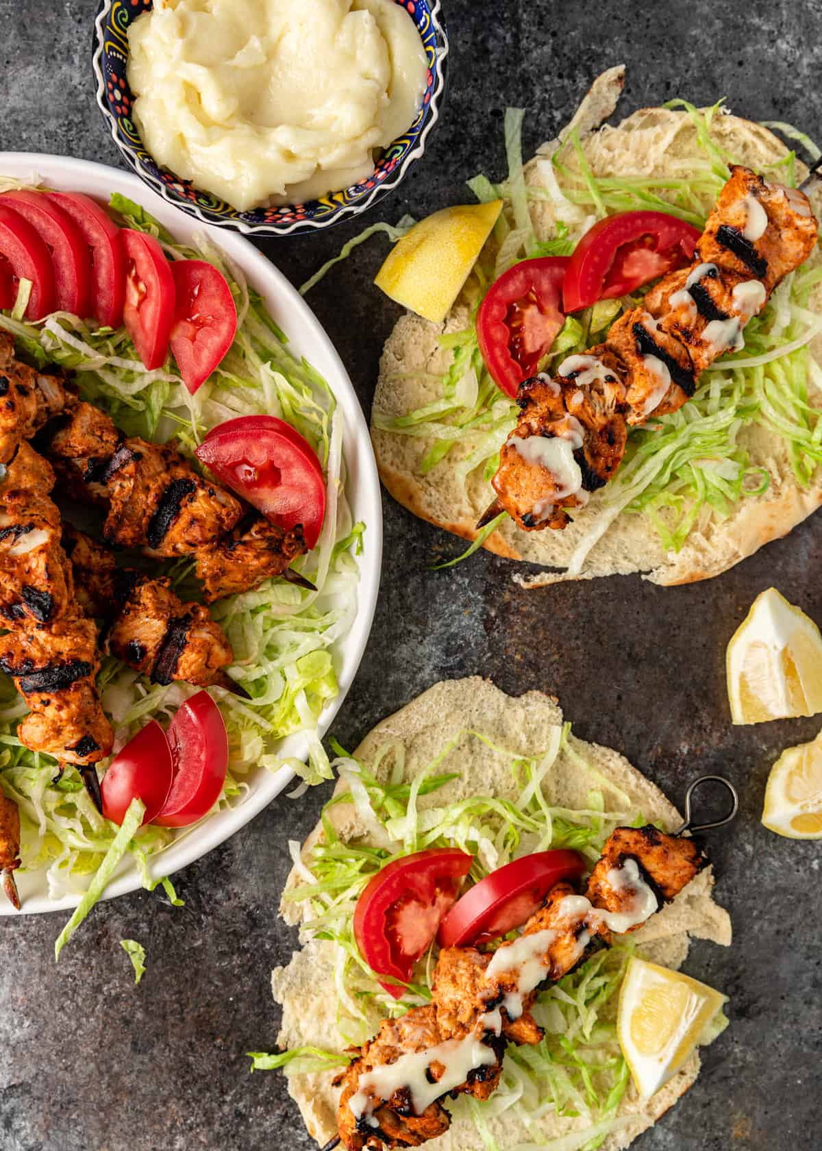 overhead: a platter full of shish tawook over lettuce and tomato with two filled pitas
