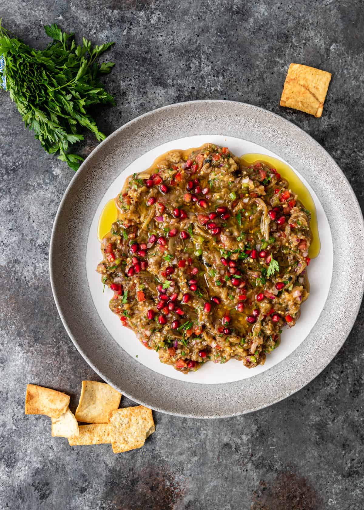 overhead: a shallow bowl full of baba ghanoush with pita chips on the side