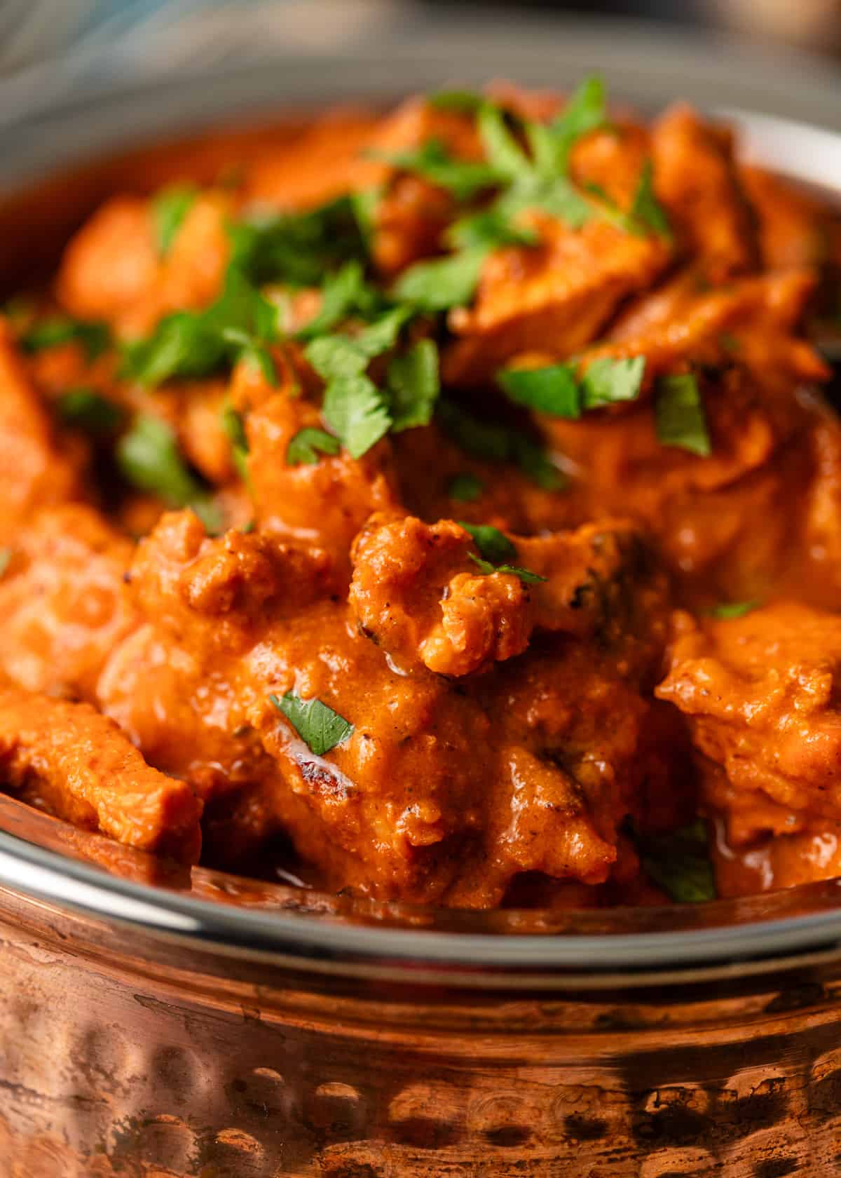 extreme closeup: chicken tikka masala with sauce and fresh herbs showing