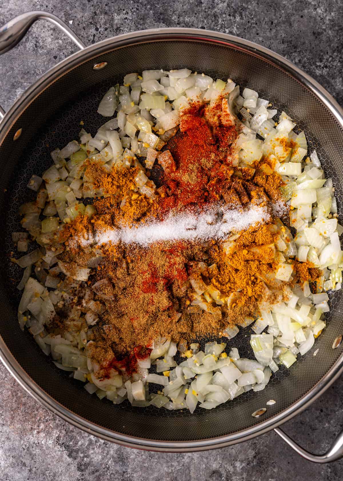 overhead: adding spices to onion, garlic, and ginger in a pot