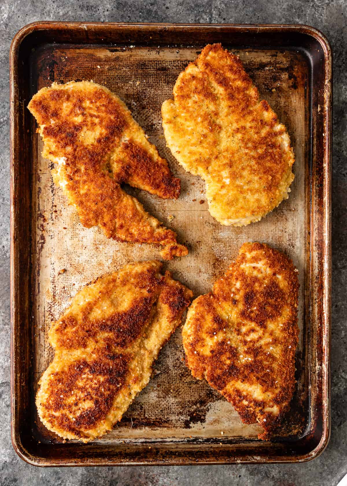 overhead: cooked breaded chicken breasts on a baking sheet