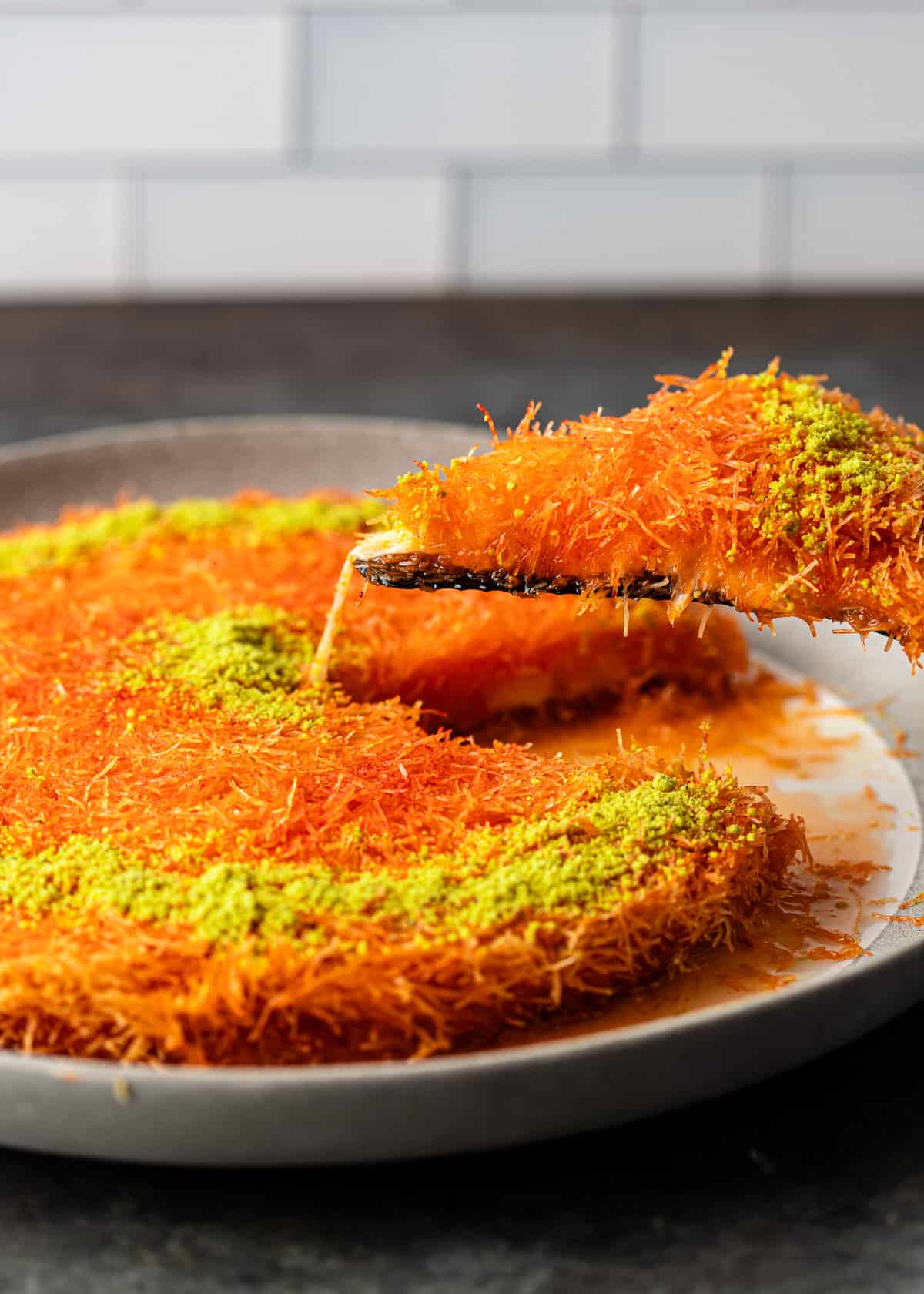 lifting a slice of knafeh out of a serving dish