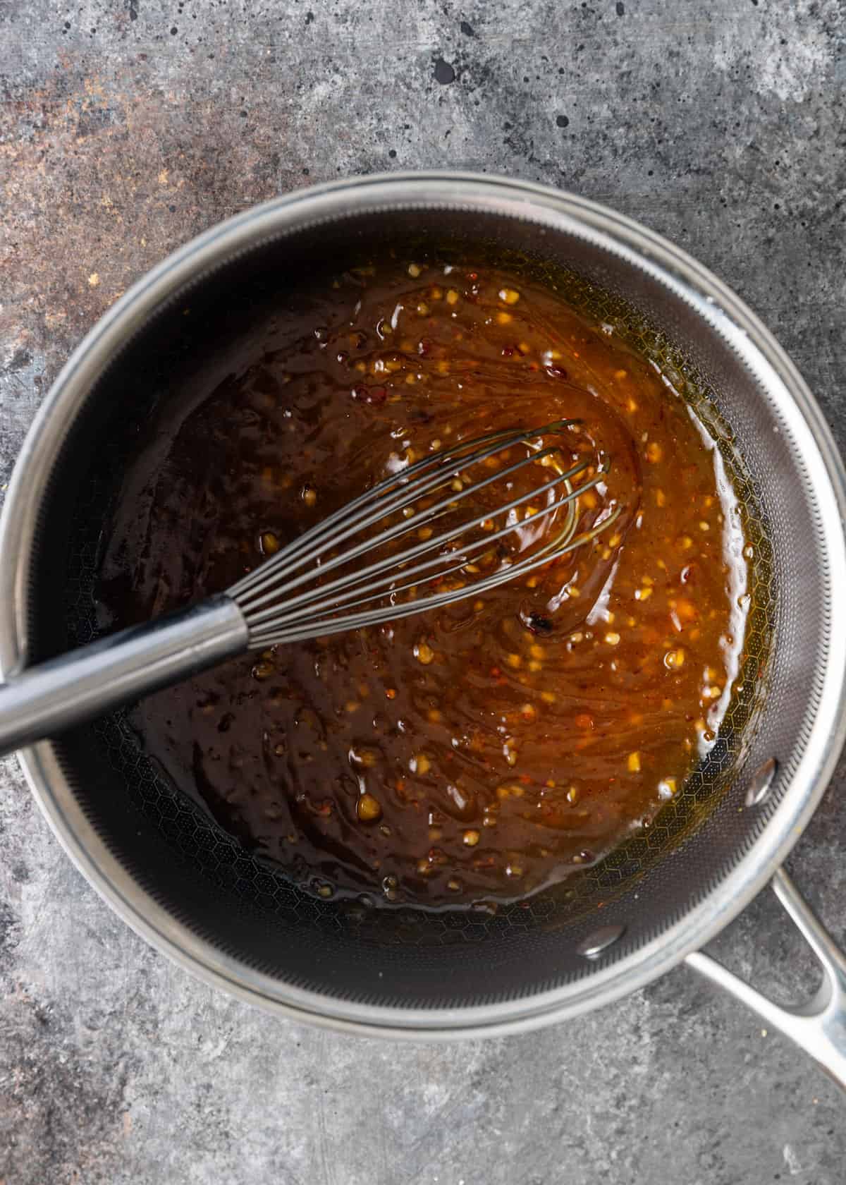 overhead: mixing the orange sauce in a large metal bowl with a whisk