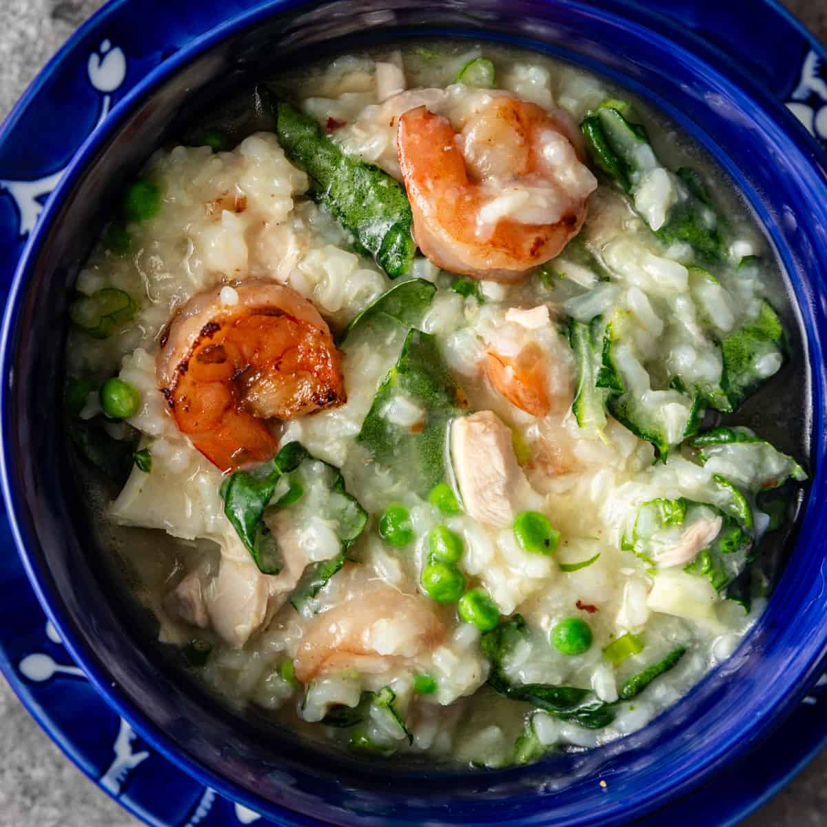 overhead: a bowl of congee with shrimp and veggies visible 