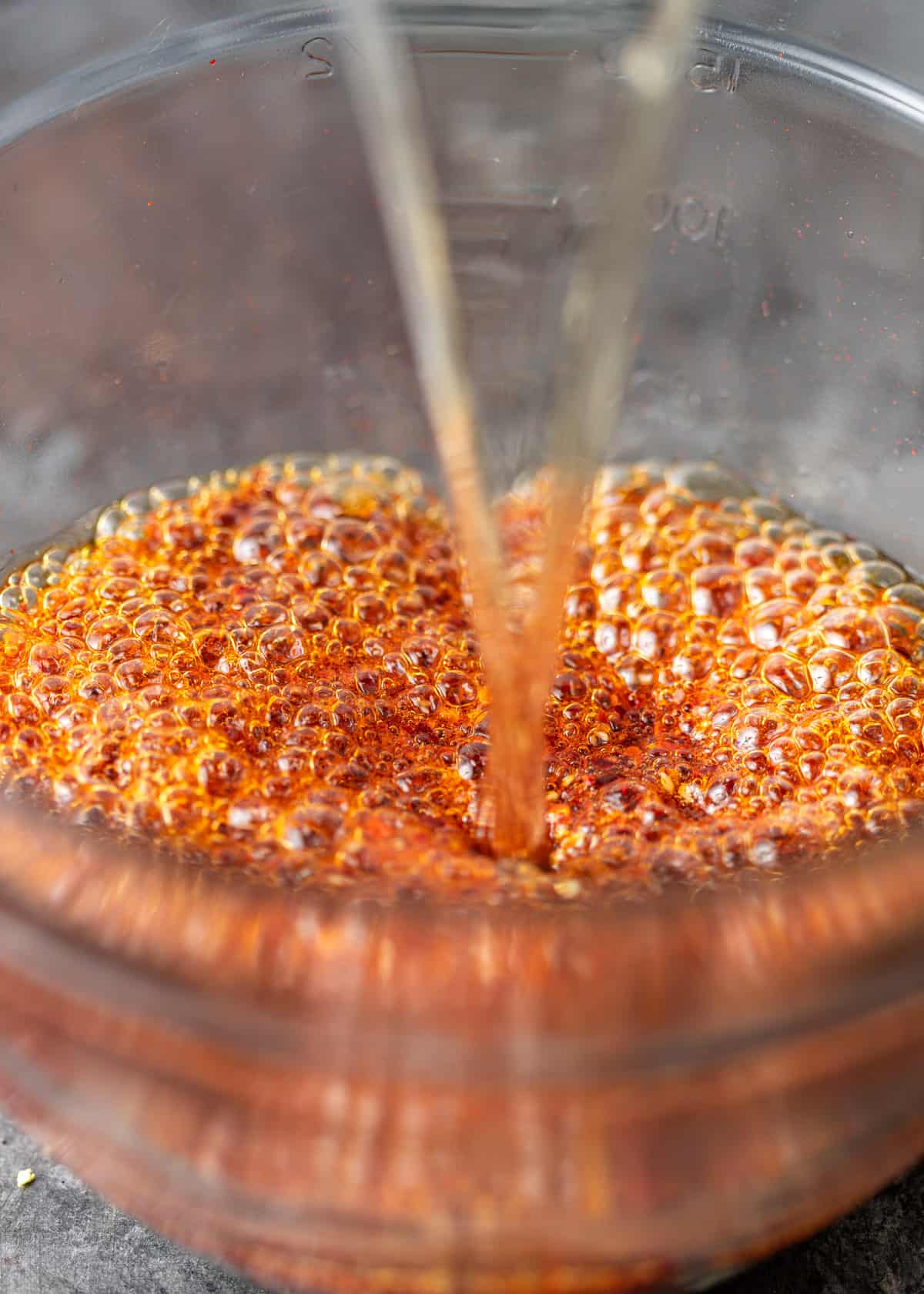 closeup: adding oil to seasonings for spicy chili crisp in a bowl