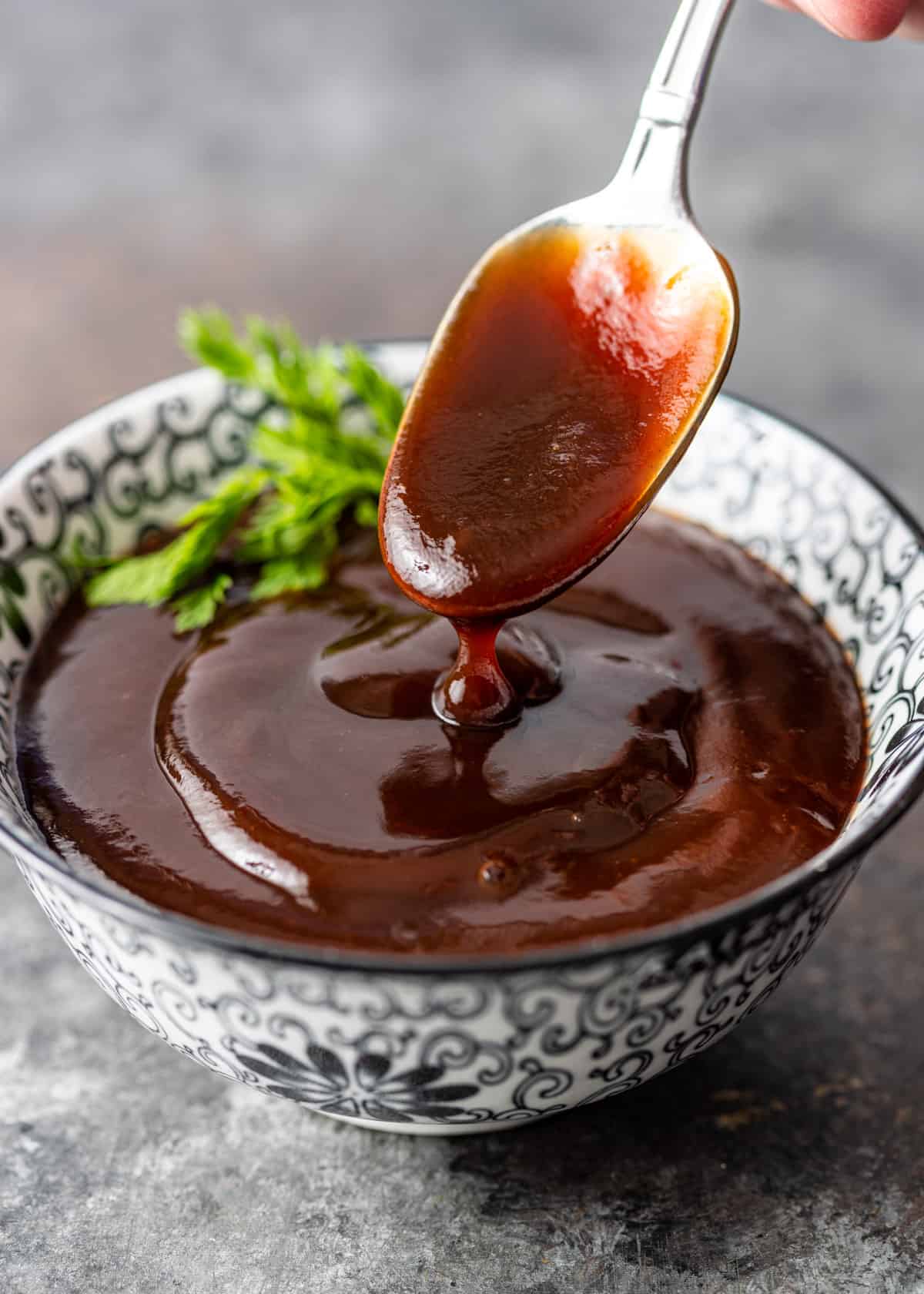 closeup: a spoon full of katsu sauce over a bowl with more sauce