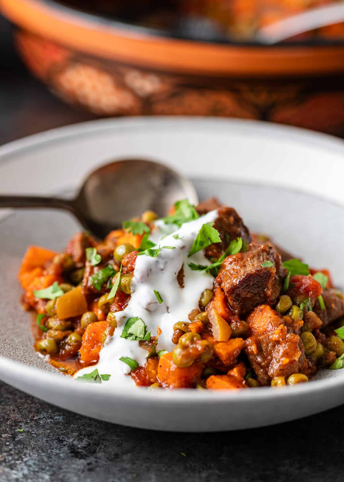 side view: beef tagine with sweet potatoes in a white dish with a white sauce on top