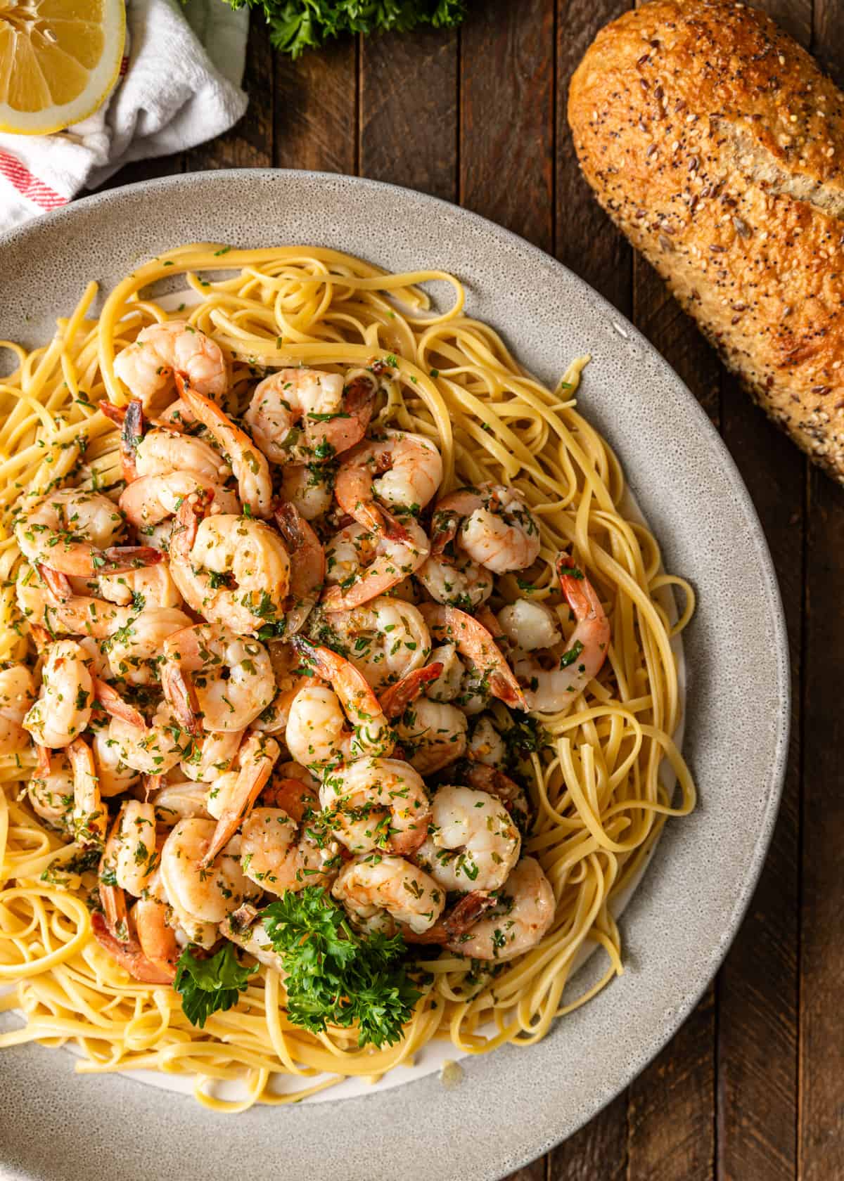 overhead: shrimp scampi pasta on a plate with bread on the side