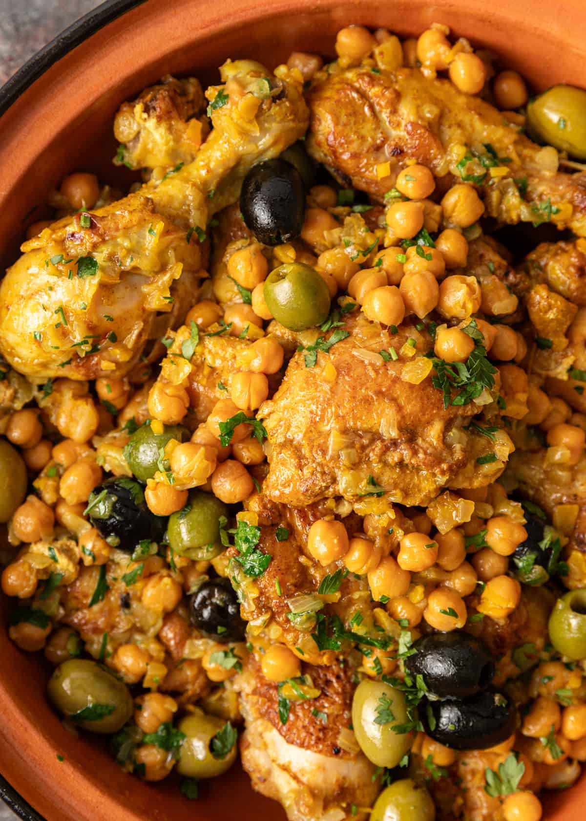 overhead closeup: chicken tagine with chickpeas and fresh herbs on top