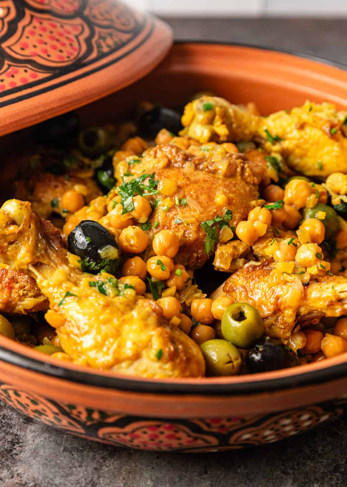 side view closeup: chicken tagine recipe with black and green olives and chickpeas showing
