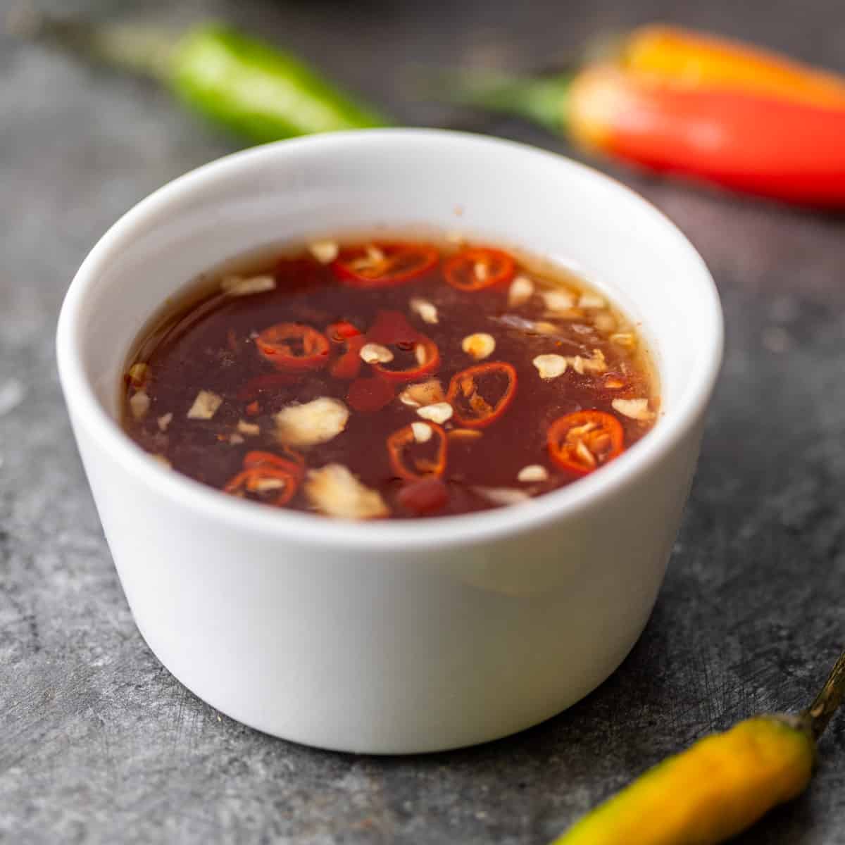 closeup: nuoc cham in a small white ramekin with peppers showing
