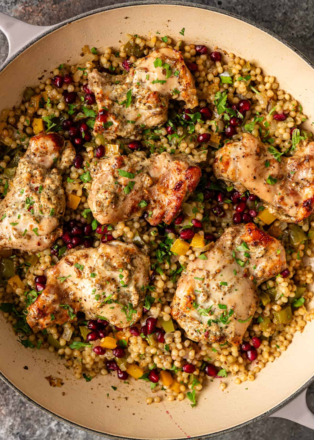 overhead: yogurt chicken recipe in a pan over pearl couscous with pomegranate