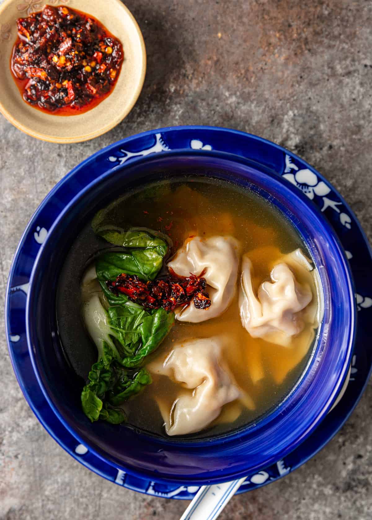 overhead: a bowl of my wonton soup recipe with chili paste and bok choy